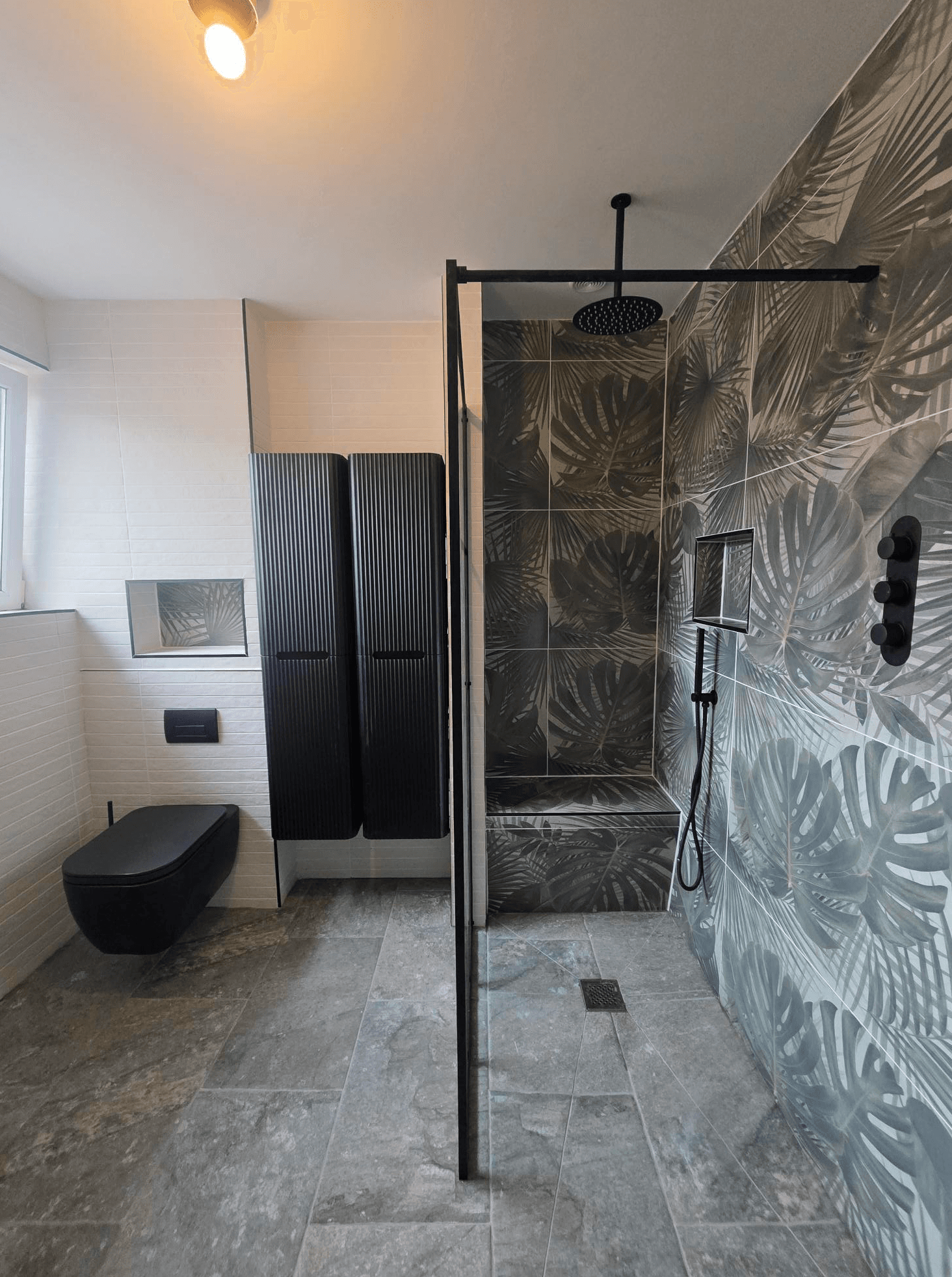 Walk-in shower with black fittings, feature leaf tiles, wall hung toilet and matching black radiator