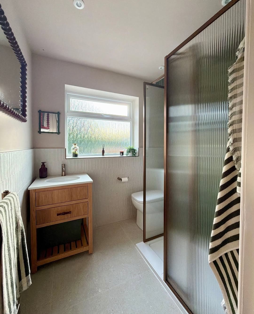 Bathroom renovation with fluted glass shower screen, timber vanity unit and warm neutral tiling